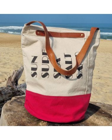 Détail du sac de plage Chloé en coton bordeaux et beige disposé sur du bois flotté, plage sauvage de Seignosse dans les Landes
