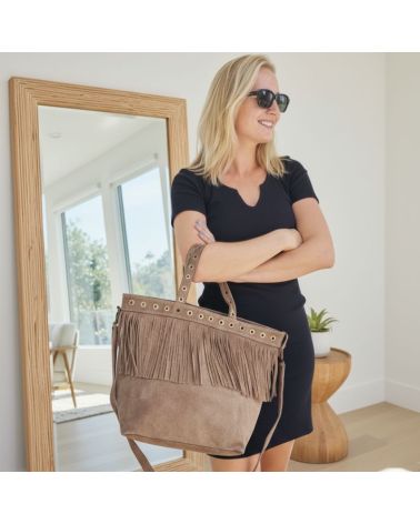 Cabas en daim taupe avec franges et œillets dorés, porté à l'épaule