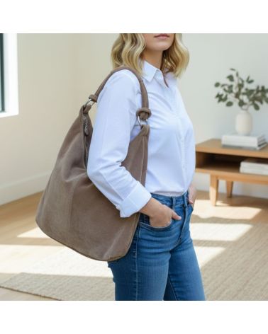 Sac hobo en daim taupe porté à l’épaule avec chemise blanche, style bohème chic