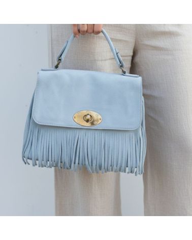 Sac à main en daim bleu ciel avec franges et fermoir doré, porté par une femme en pantalon de lin beige