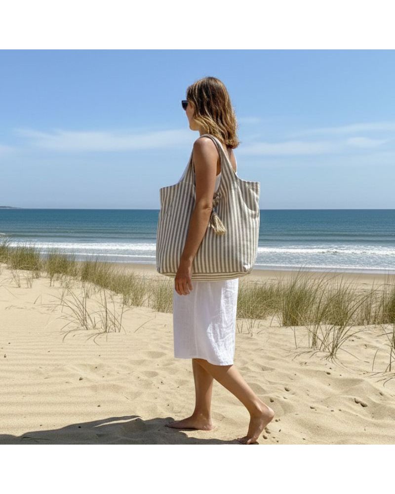 Sac de plage rayé camel et blanc Marinella en coton grand format avec fermeture zippée sur la plage face à l’océan