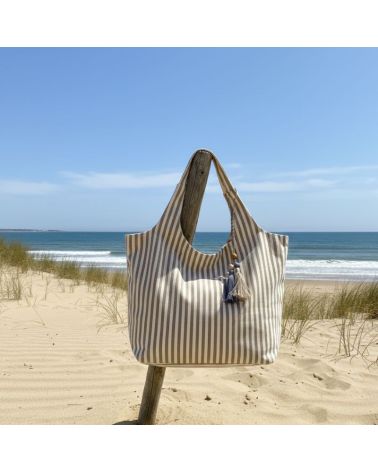 Sac de plage rayé camel et blanc Marinella en coton grand format avec fermeture zippée sur la plage face à l’océan
