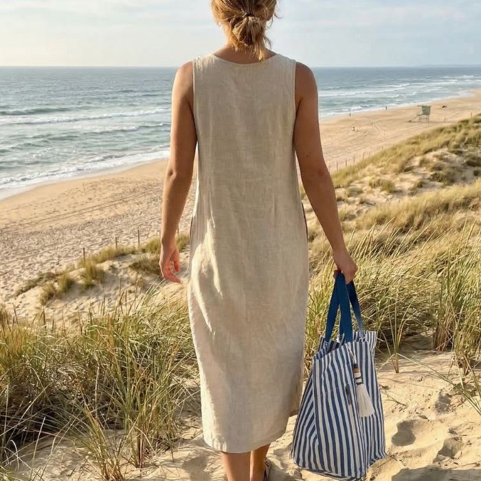 sac de plage rayé porté par une femme marchant au bord de l’océan