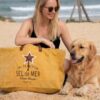 Grand sac de plage XXL "Sel de Mer" coloris jaune safran posé sur le sable à côté d'un chien Golden Retriever. Cabas éco-responsable en toile recyclée et anses en cuir, idéal pour les vacances et les sorties estivales