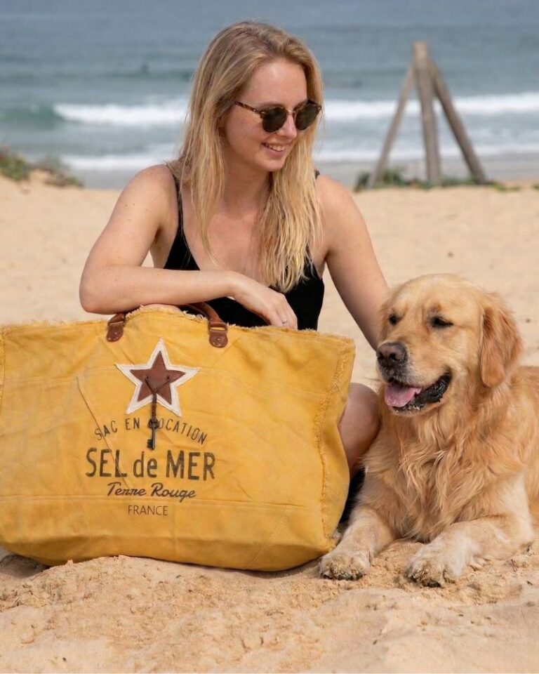 Grand sac de plage XXL "Sel de Mer" coloris jaune safran posé sur le sable à côté d'un chien Golden Retriever. Cabas éco-responsable en toile recyclée et anses en cuir, idéal pour les vacances et les sorties estivales