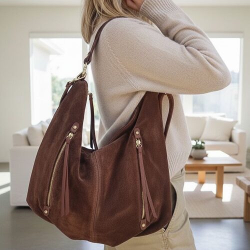 Sac en daim marron porté à l'épaule, style bohème chic avec poches zippées