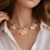 Collier doré Mile mila avec cordon tressé, chaîne mêlée et breloques feuilles sur un modèle portant une chemise blanche