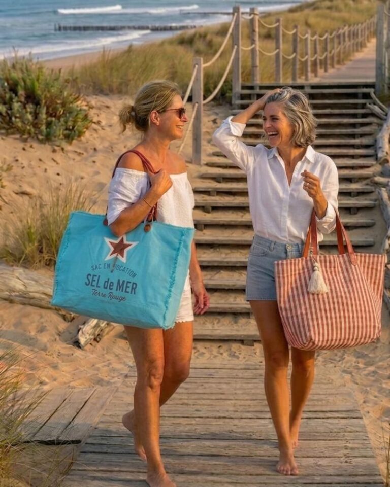 deux femmes souriantes sur une plage de dunes portant des sacs de plage cabas colorés, idée cadeau femme