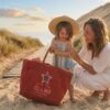 Une femme et une petite fille sur la plage avec un grand sac de plage rouge Sel de Mer en toile recyclée.